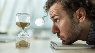 A scientist dejectively observes an hourglass because of his fixed-term contract act